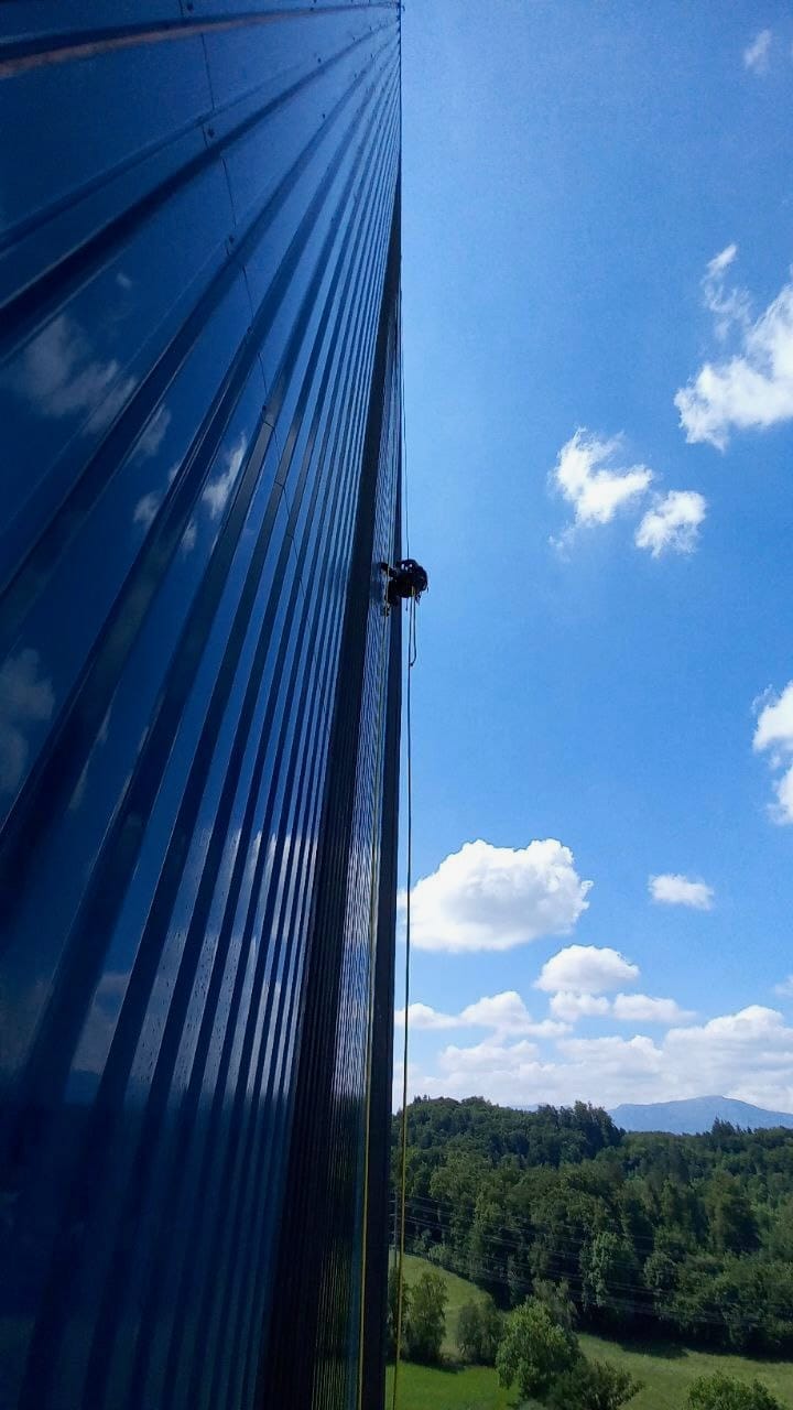 Τεχνικοί που πλένουν πρόσοψη χρησιμοποιώντας πρόσβαση με σχοινί